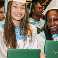 <p>Two students holding up their diplomas.</p>