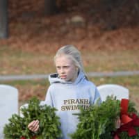 <p>Darien Piranha fifth grader Emily Kalvaitis places two wreaths at Spring Grove Cemetery.</p>