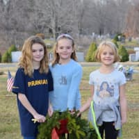 <p>Olivia Stramandinoli, Miller Ward and Shea Ward of the Darien YMCA Piranhas place wreaths at Spring Grove Cemetery.</p>