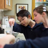 <p>Students peer into a bowl as they make yogurt during a Nutrition Week activity Tuesday at Ridgefield Academy. </p>