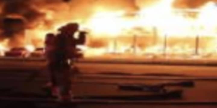 A firefighter battles the intense blaze at a car dealership where an HBO mini-series was filming.