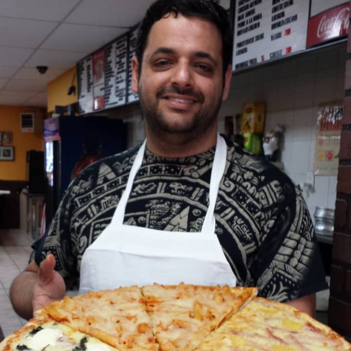 Frank Daher with a platter of many different types of pizza pies.