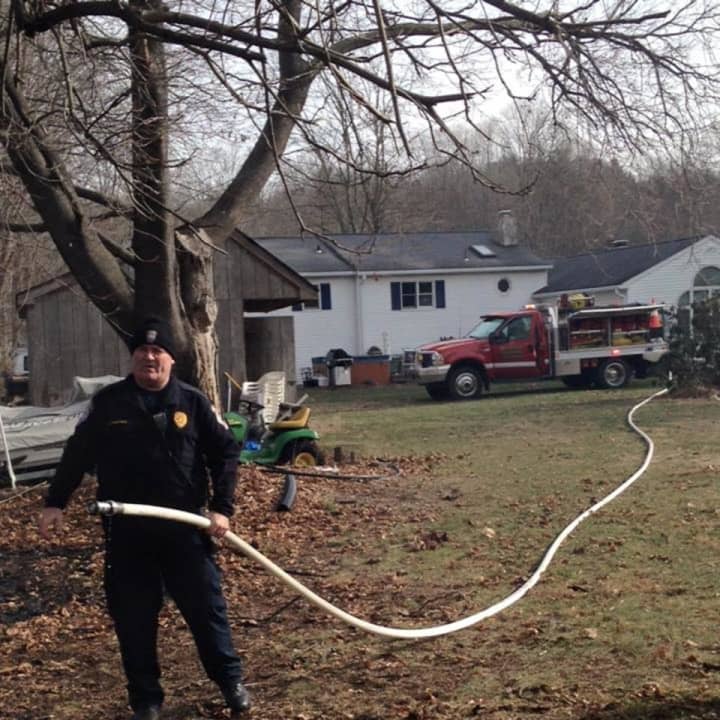 One of Brookfield&#x27;s commanding police officers, Maj. James Purcell, stretches the hose line. Purcell helped extinguish a brush fire Friday morning.