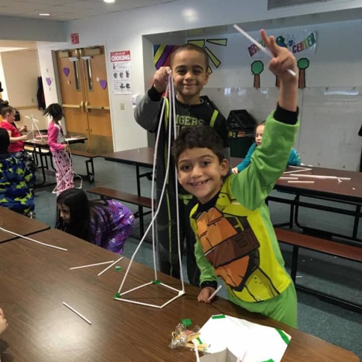 Kids creating a tower out of straws.