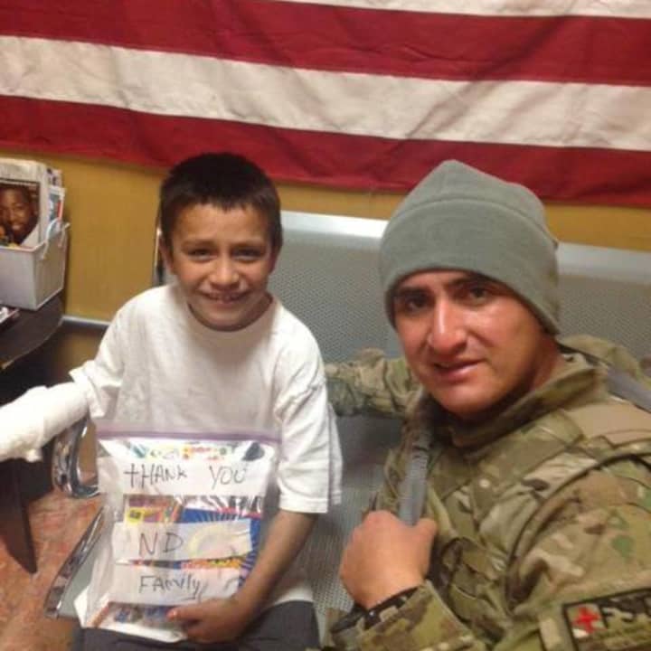 Fernando Moreno-Rivas, right, who was killed in a wrong-way crash on Route 8, presents gifts to an Afghanistan boy in 2012. Funeral services for the former Stratford resident and Army medic were held in Fairfield Tuesday.
