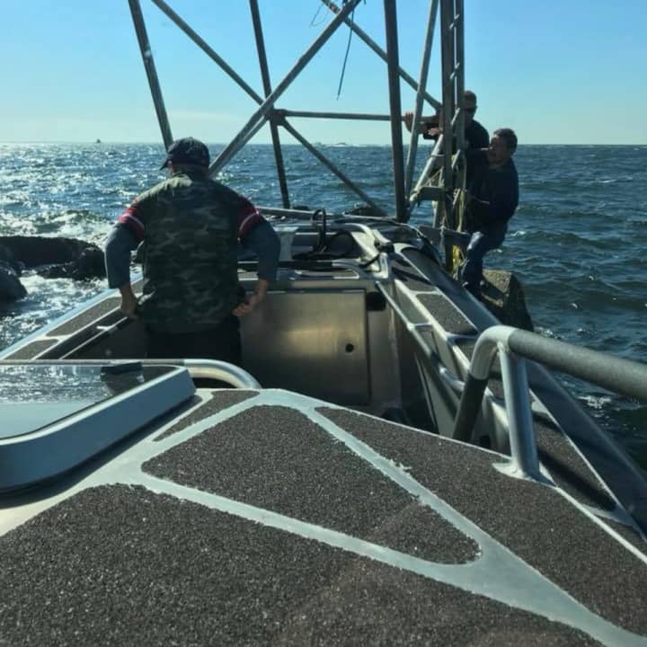 Fairfield marine police respond to the 2A navigational marker off Black Rock Harbor to rescue two men whose boat overturned.