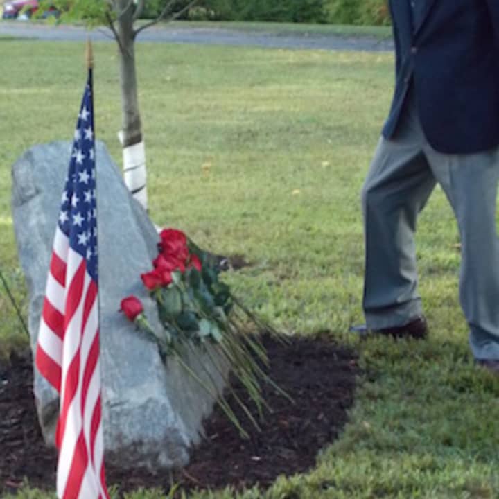Darien veteran Charles Scribner places a rose at the base of the 9/11 Memorial behind Middlesex Middle School.