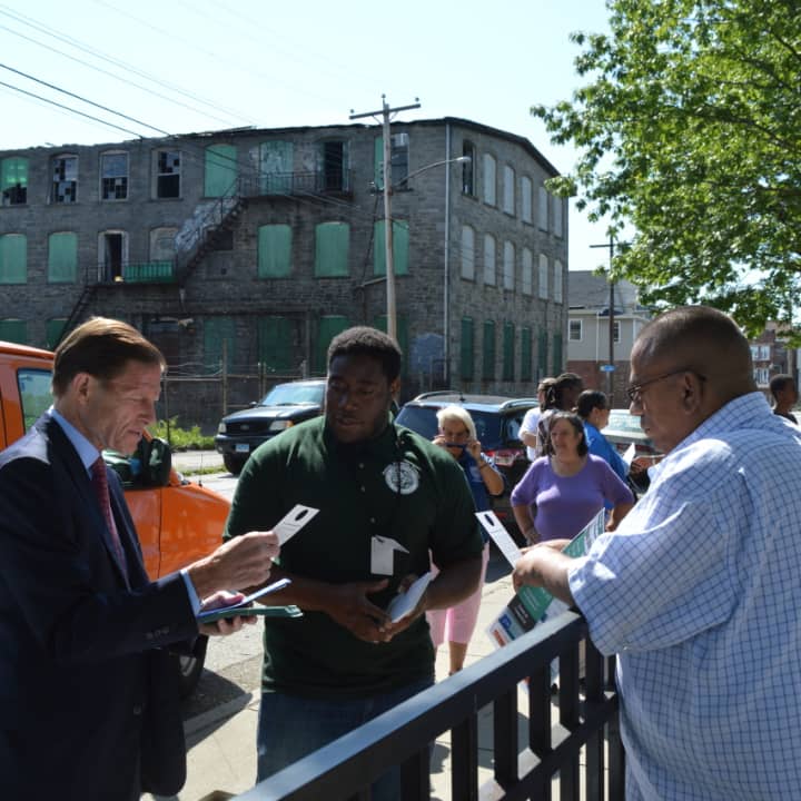 U.S. Sen. Richard Blumenthal, left, and Jonathan James, center, a public health associate with the Bridgeport Health Department, share information on mosquito-borne illnesses with residents of the city&#x27;s Hollow neighborhood.