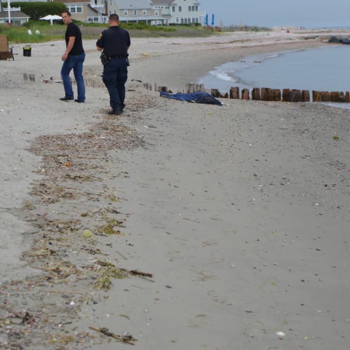 Fairfield police wait with the body of a man who washed up on shore Thursday afternoon.