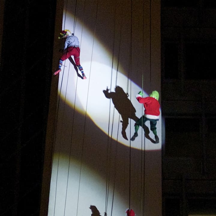 Mrs Claus, The Grinch and Cash Elf rappel down Landmark Square in downtown Stamford.