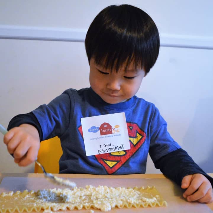 This little boy in the HealthBarn USA Seedlings program can&#x27;t be too precise spreading the cheese mixture on his lasagna noodle.