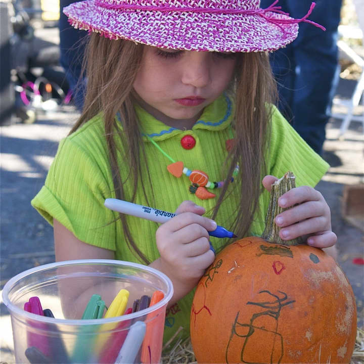 A girl paints a pumpkin at Sunday&#x27;s Harvest Fest.