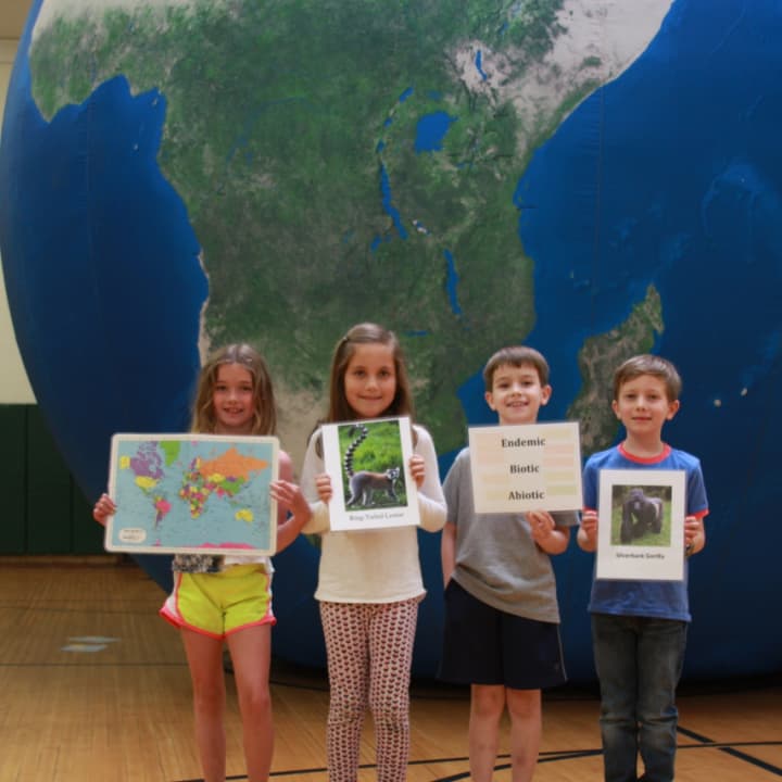 Holmes School second-graders Maeve Brennan, Winnie Wartels, Matthew DelVecchio and Tommy Galligan pose with the Earth Balloon in the Holmes School gym in Darien.
