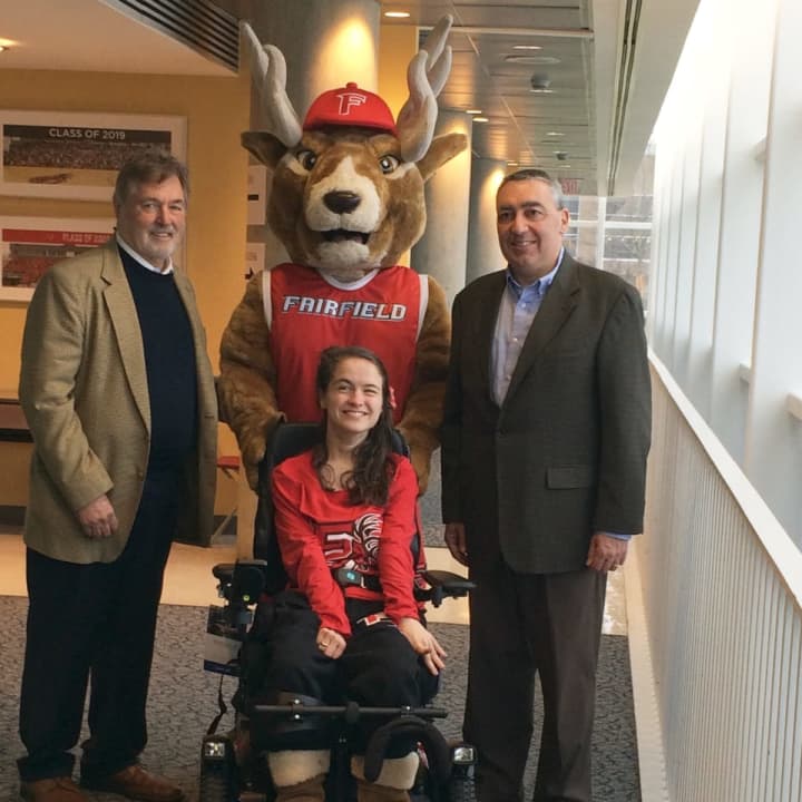 Meg Moore, center, poses with Fairfield University alumni Robert Berchem, left, and Bryan LeClerc, right, and Lucas, the Fairfield Stag mascot.