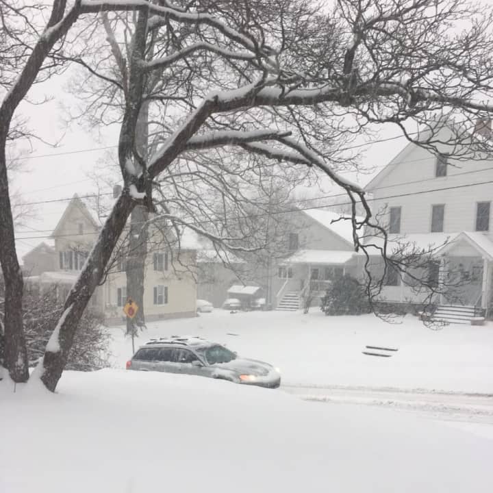 A heavy blanket of snow already covers Danbury at 8 a.m. Thursday as a car heads up a residential street.