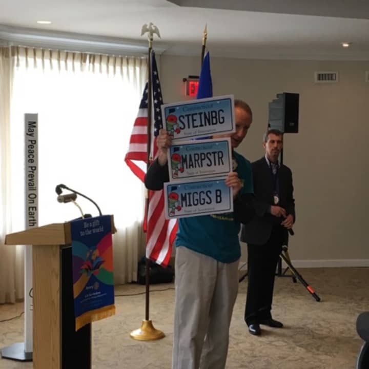 Mark Mathias, creator of the Maker Faire, holding up prospective Maker Faire-related vanity plates at Westport Sunrise Rotary. From top, Rep. Jonathan Steinberg, First Selectman Jim Marpe and multi-media artist and man about town Miggs Burroughs.