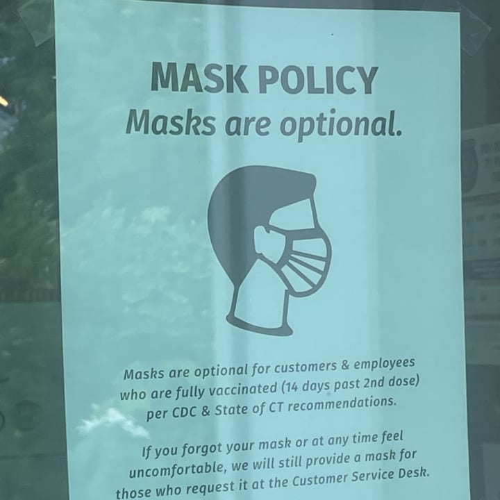 A sign posted at a store stating its mask policy, saying masks are optional for those fully vaccinated for COVID-19.