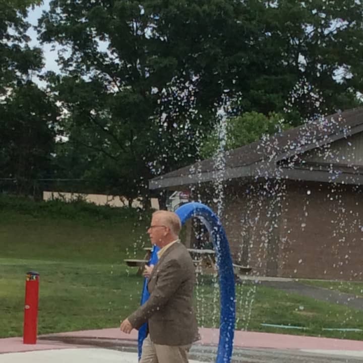 Danbury Mayor Mark Boughton dodges the drops at the new spray park at Kenosia Park.