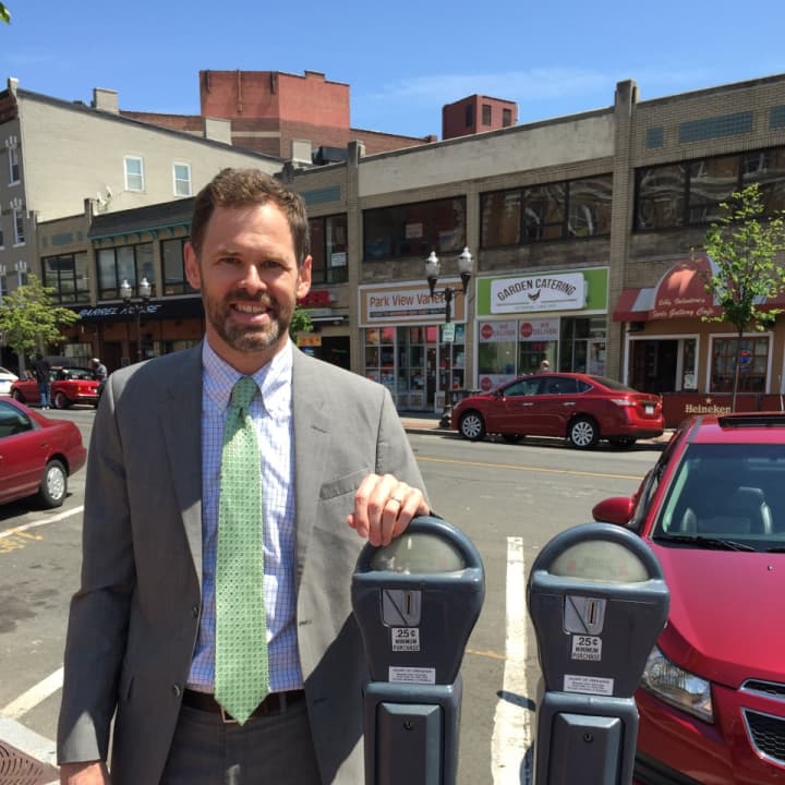 Bureau Chief of Transportation, Traffic &amp; Parking Josh Benson poses for a photo at a parking meter in downtown Stamford.