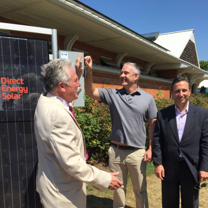 Norwalk Mayor Harry Rilling flips a ceremonial switch on a solar array Wednesday morning along with state Sen. Bob Duff.