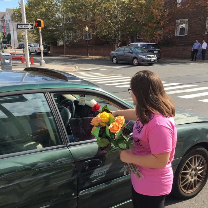 Victoria Colangelo of Stamford, a volunteer with Stamford Florist, hands out free flowers on Wednesday on Summer Street.