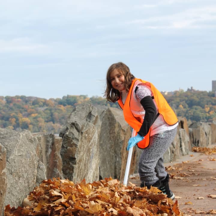 Lillian Simhon, 10, clears leaves near Ross Dock in Fort Lee during the Jewish Youth Encounter volunteer cleanup event. 