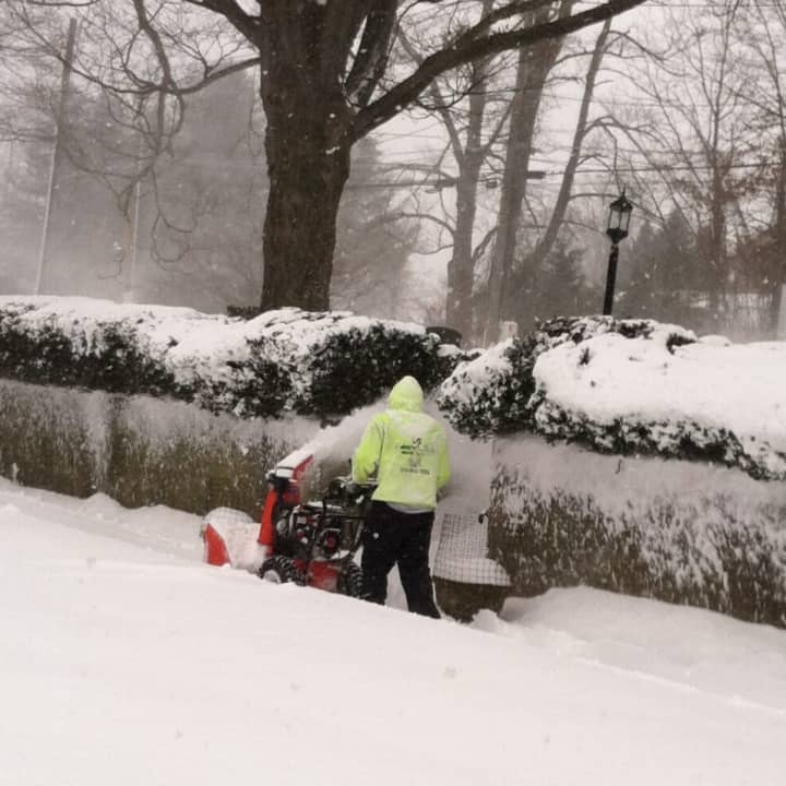 A man pushes a snowblower.