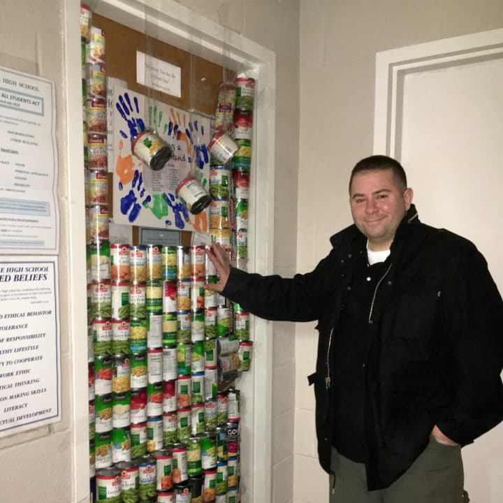 Nick DiPaolo stands in front of his office door, which was barricaded with cans of food by his high school colleagues.