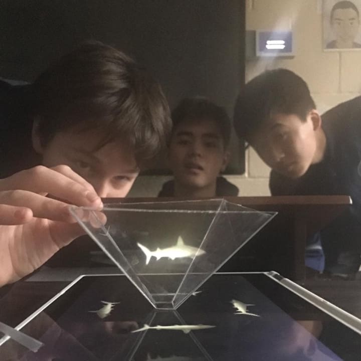 The students have been studying about the properties of trapezoids and exploring how to create projections using different angles; they applied this knowledge into making the holograms.