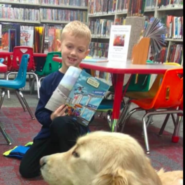 Kids can read to Thatcher, the therapy dog, at the library&#x27;s ongoing Paws to Read program.