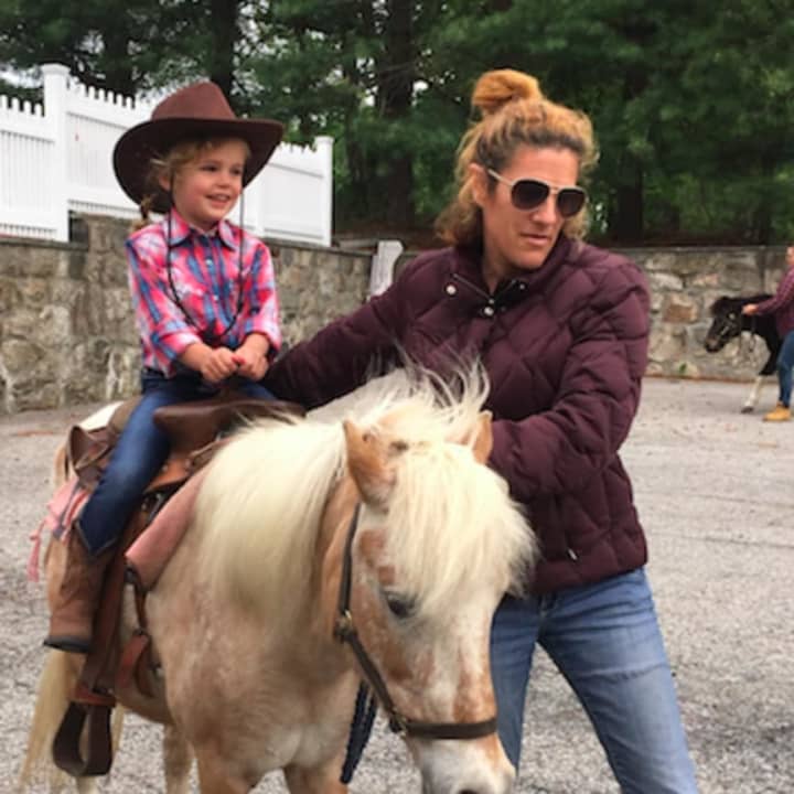 Round Hill Nursery School student Grace O&#x27;Sullivan, 3, rides, Hunny, 16, a Shetland Pony mix during Western Day at the school Friday. Also pictured is Jessica Pavella, who is guiding the pony.
