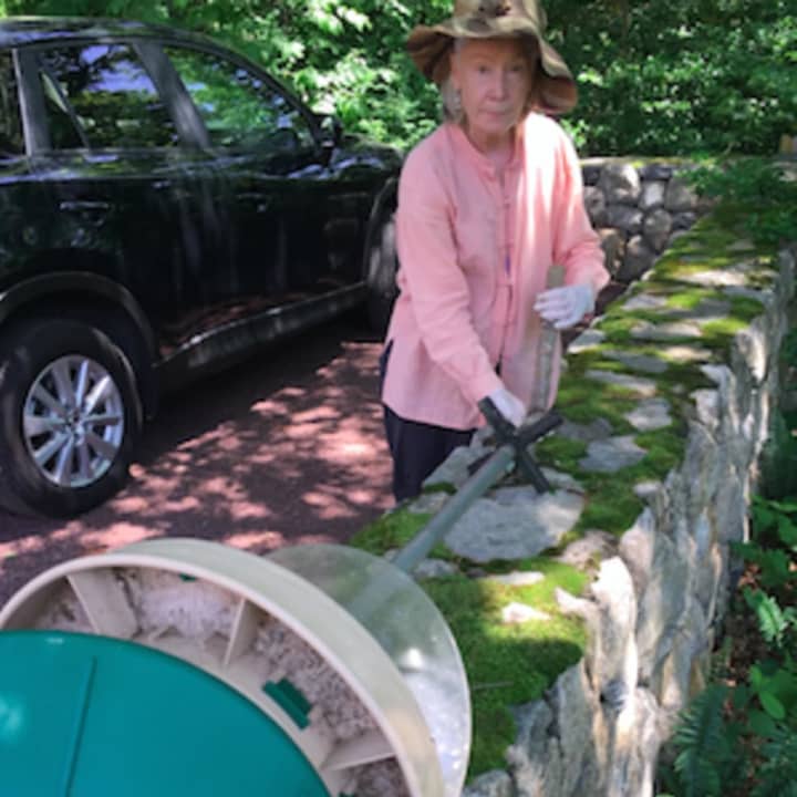 Landscaper Christine Cook holds the bent base of a bird feeder that she believed was damaged by a bear looking for food at an Oenoke Lane property in New Canaan Tuesday.