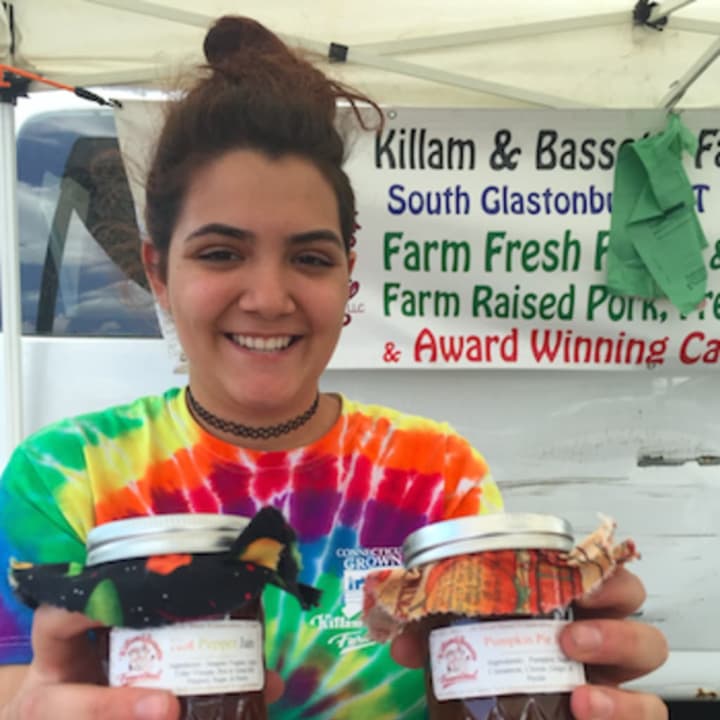 Valentina Pinzon holding a couple of bottles of Killiam &amp; Bassette Farmstead jams at the Danbury Farmers Market on Saturday. The business is in South Glastonbury. The market opened Saturday and runs until Oct. 22.