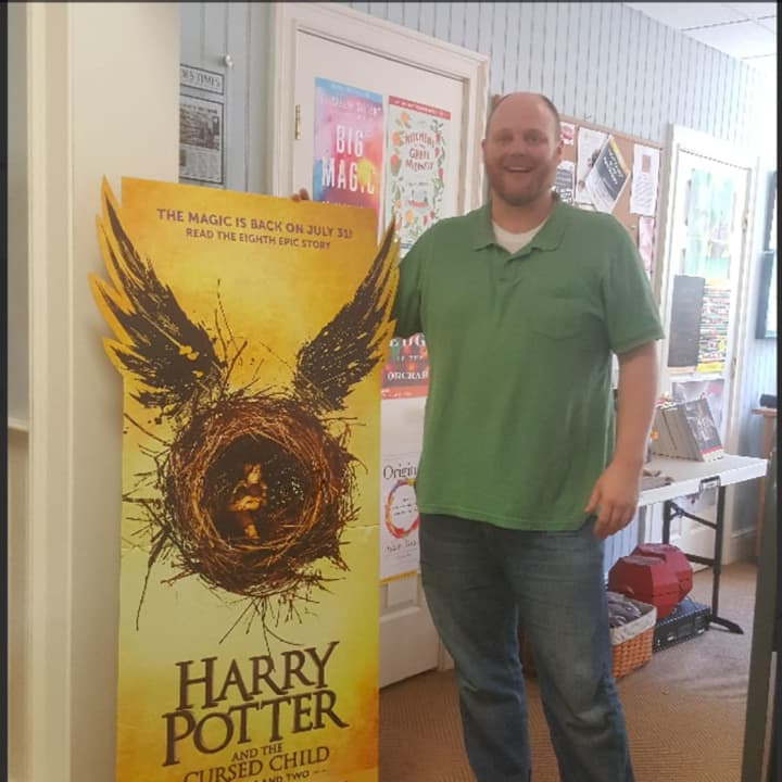 Steve Hutchinson of Byrd&#x27;s Books in Bethel, poses by the poster for Harry Potter&#x27;s newest book -- &quot;Harry Potter and the Cursed Child -- Parts I &amp; II.&quot; The newest book is releasing on July 31.
