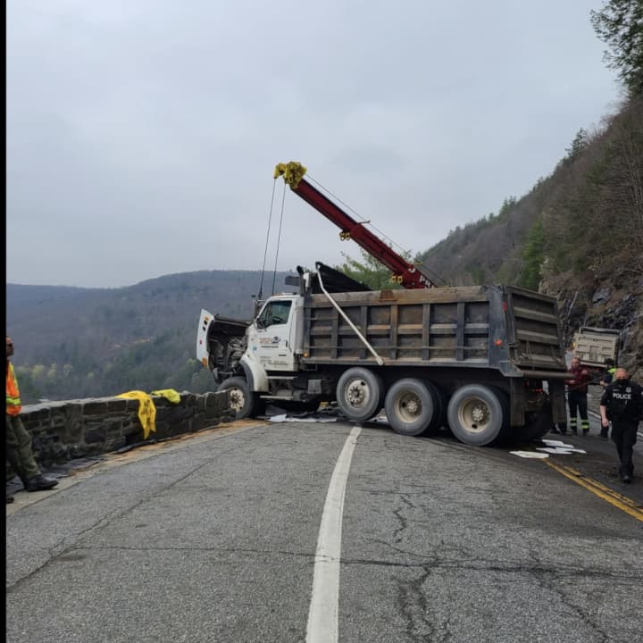 A dump truck almost went over a mountain and into the river below after crashing into a rock retaining wall.