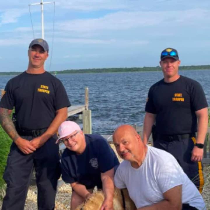 Golden Catch: New Jersey state troopers Ryan Koehler, left, and Vincent Ferdinandi, far right, with the grateful owners of Chunk, a Golden Retriever missing the past 16 days. The dog was found swimming off the Jersey Shore.