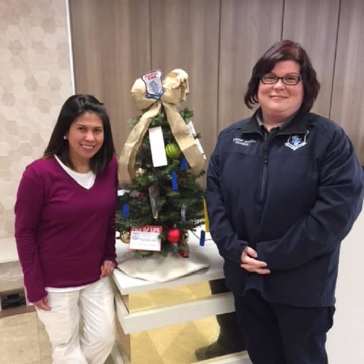 Simonette Castaneda, Regional MDS Director for Cassena Care of Stamford accepts a donated tree from Jessica Anderson, Stamford EMS Lieutenant and Academy Training Coordinator, for the fourth annual Festival of Trees