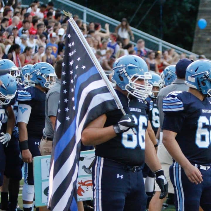 Co-Captain of Wayne Valley High School&#x27;s football team Jake Pluta carries the &quot;Thin Blue Line flag&quot; during the home field opener against Lakeland High School.