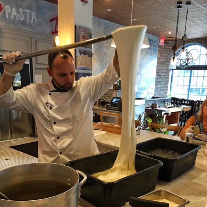 A chef stretches dough at Pax Romana in White Plains. The restaurant is reviewed in The New York Times.