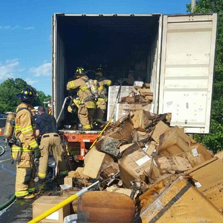 Firefighters empty the contents of a tractor-trailer after a fire Wednesday afternoon on I-95 in Stamford.
