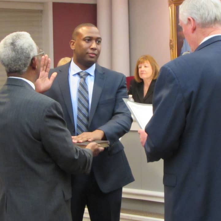 New Fair Lawn Police Officer Brian Goodson is sworn in by Mayor John Cosgrove, while his father, Eugene, holds the Bible.