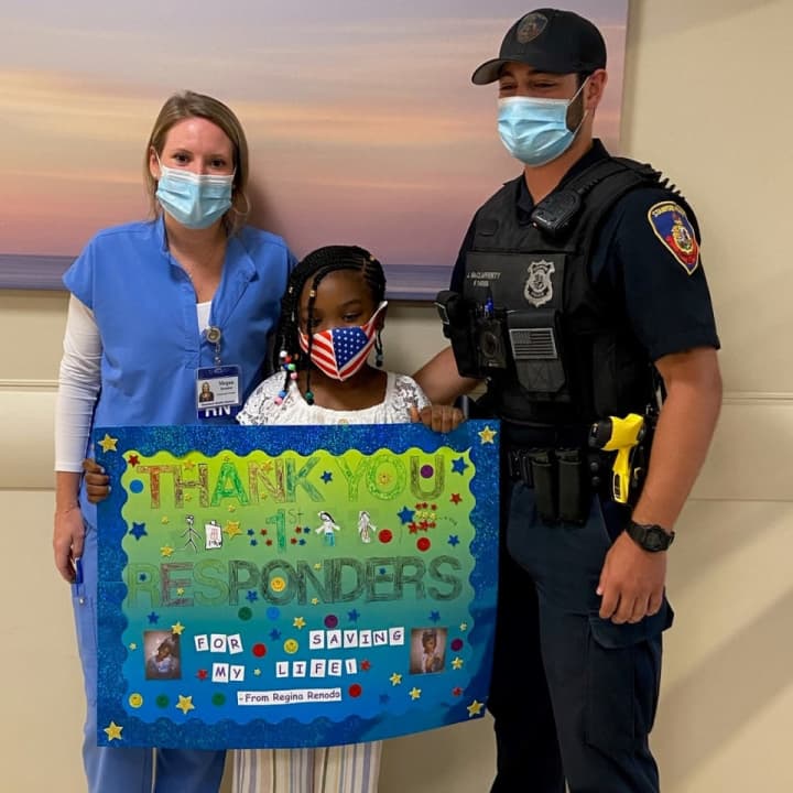 Regina Renodo thanks her rescuers, Megan Donahue and Officer John McClafferty, with a homemade sign at Stamford Hospital
