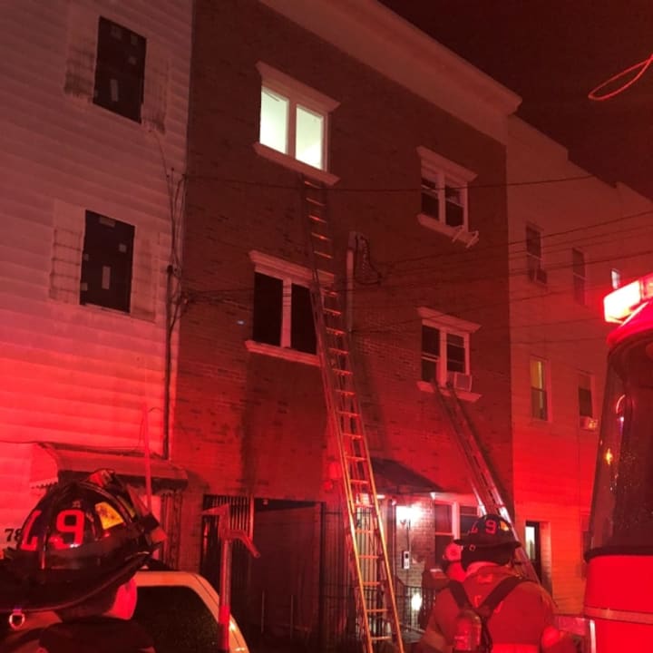 Firefighters stretch a ladder to the third floor of 76 Hutton St., to rescue a victim trapped above the fire.