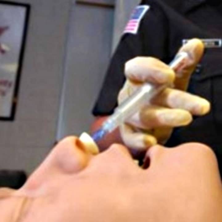 An officer administers Narcan to a practice dummy.