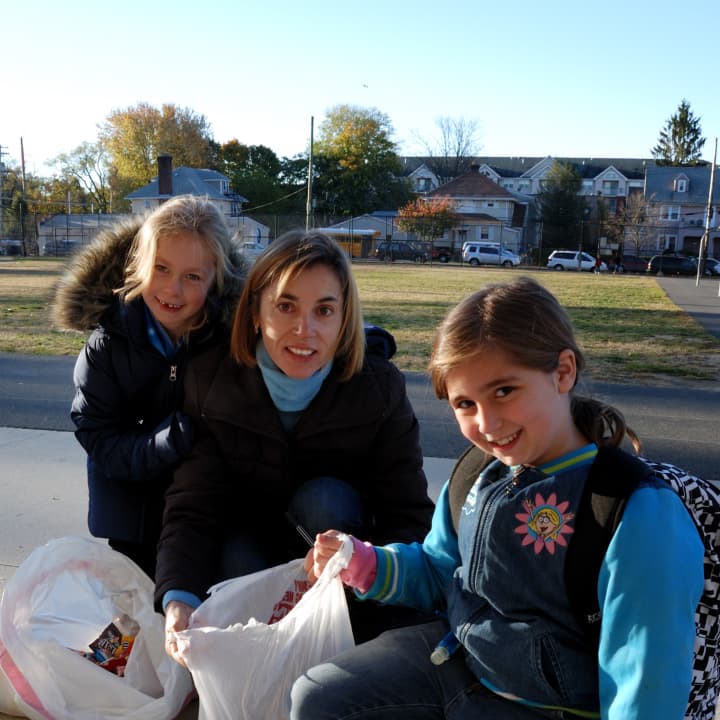 Hilde Friderichs, center, collects candy for the Halloween Candy Exchange at Mamaroneck Avenue School with the help of two students.