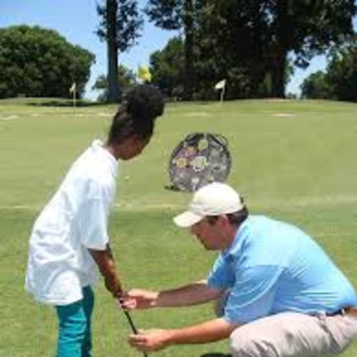 Instructor Rick Nielsen helping a New Rochelle camper with her putting.