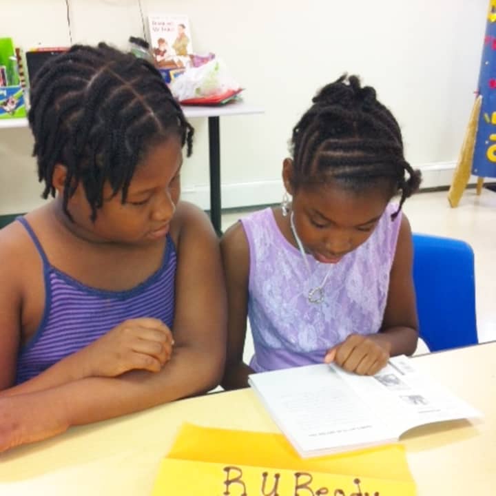 Book Buddies Markell Spencer of Roodner Court and Talishka Antoine of Washington Village share a book in the 2013 NHA Summer Literacy Program funded by Fairfield County Community Foundation.