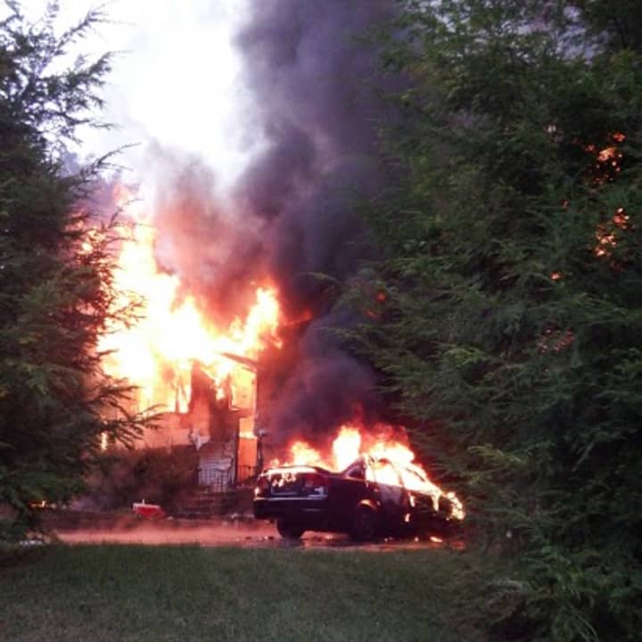 A fire engulfs the home and a car at 1 Crestwood Drive in Danbury on Tuesday. 