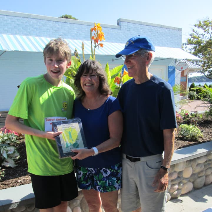The youngest runner in the 16th annual Ian James Eaccarino Memorial Nine-Mile Race, Jonathan Tinker, receives an award from Ginger and Larry Katz.