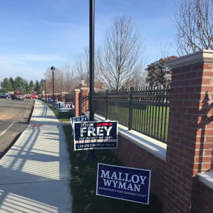 Signs line the walkway and fence In front of the Ridgefield Playhouse and Governor Park as residents head to vote Tuesday.